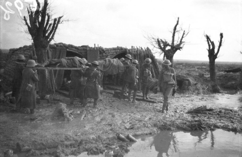 A German prisoner assists in carrying in a stretcher through the mud at Gravenstafel Ridge.